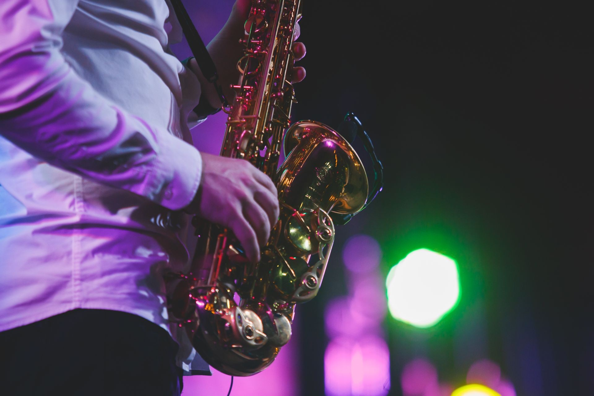 Concert view of a saxophone player with vocalist and musical jazz band in the background
